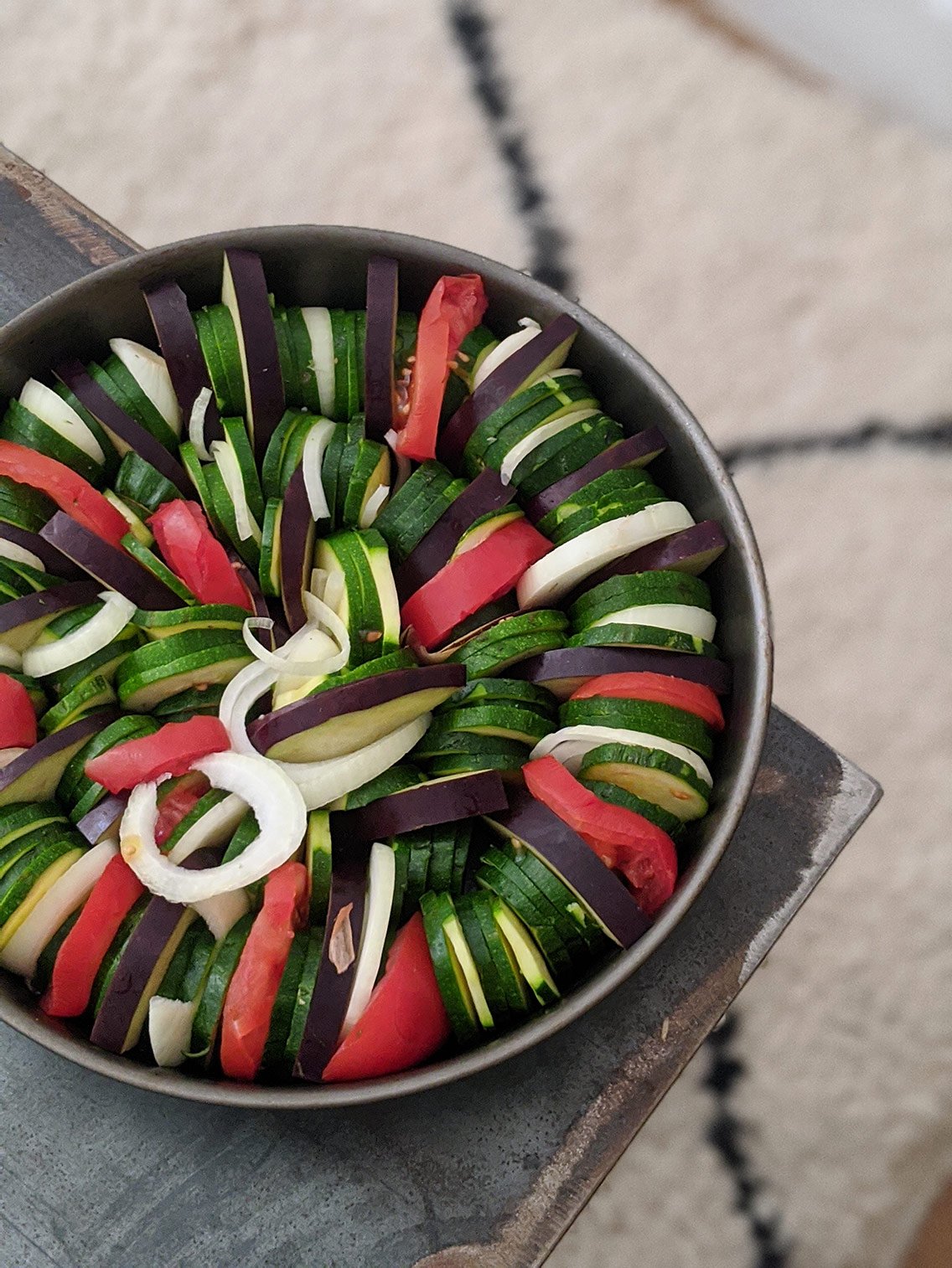 Après avoir huilé mon plat, j'intercale les différents légumes entre eux dans un plat rond, ovale, ou carré. Je les place de manière circulaire et je veille à ce qu'ils soient bien serrés. (Petite astuce : si vous avez un plat en terre cuite, trempez-le 30 minutes dans l'eau avant d'y mettre les légumes, ça permettra une cuisson plus "à la vapeur")