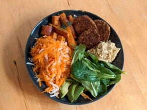 Bowl coloré aux carottes, patates douces, avocat, mâche, radis noir, houmous et falafel